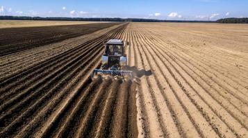 traktor - flygfoto av en traktor på jobbet - odlar en åker på våren med blå himmel - jordbruksmaskiner foto