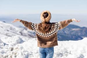 ung kvinna njuter av de snöiga bergen på vintern foto