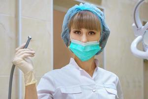 en kvinnlig tandläkare håller en bormaskin i handen foto