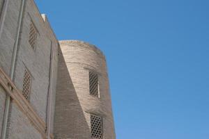 en gammal tegelbyggnad med ett torn. antika byggnader i medeltida asien. bukhara, uzbekistan foto