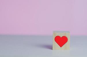 träkuber med kärlekssymbol hjärta rött på den rosa bakgrunden och kopieringsutrymme. foto