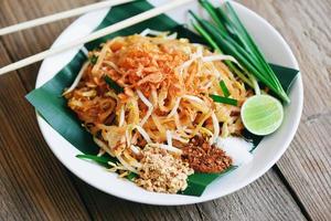 woka nudel pad thai på tallrik serverad på matbordet mat, thailändsk mat stekt nudel thai stil med räkor böngroddar och garnering jordnötter chili pulver socker citron lime - ovanifrån foto