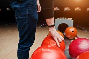 närbild av bowlingspelare hand tar röd boll från skål hiss foto