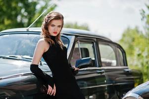 porträtt av vacker mode flicka modell med ljus makeup i retrostil lutade sig mot en veteranbil foto
