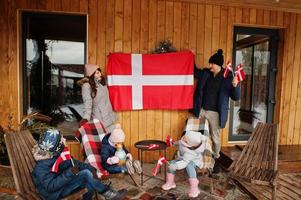 familj med danmarksflaggor nära de trähus. resa till skandinaviska länder. lyckligaste danskarnas . foto