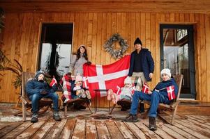 familj med danmarksflaggor nära de trähus. resa till skandinaviska länder. lyckligaste danskarnas . foto