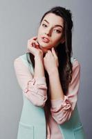 närbild ansikte porträtt av ung brunett flicka bär i rosa blus, turkos jacka, slitna jeans. mode studio skott foto