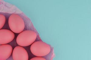 rosa påskmålade ägg på skrynkligt omslagspapper. blå bakgrund. foto