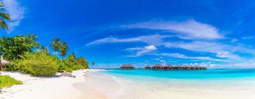 fantastiskt panorama på Maldiverna. lyxiga resortvillor havslandskap med palmer, vit sand och blå himmel. vackert sommarlandskap. fantastisk strand bakgrund för semester semester. paradisön koncept foto