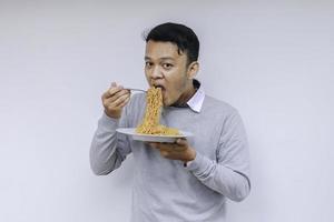 ung asiatisk man njuta av nudlar. äta lunch koncept foto