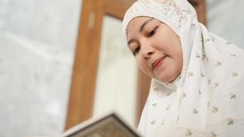 asiatisk muslimsk kvinna som läser koranen i moskén foto