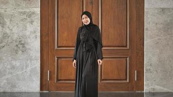 kvinna i svart muslimsk klänning som ler ser vacker ut i moskén foto