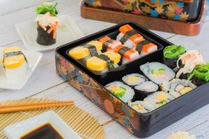 set med olika sushi, tamagoyaki, crabsticks sushi och maki i bento box serveras med sojasås och wasabi. utsökt japansk mat. foto