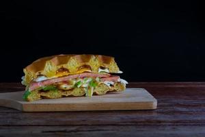 våffelsmörgås med färsk sallad, stekt ägg och skinka med tomatsås på skärbräda och svart bakgrund. kopiera utrymme för din text. foto