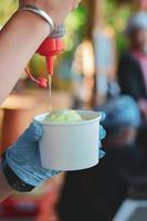 häll söt honung på avokadoglass i pappersskål till hands. minska plast skål koncept. foto