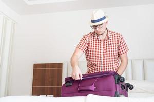 stilig kaukasisk ung man packar sin resväska för resor foto