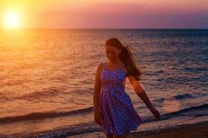 flicka går på stranden i solnedgången, koppla av foto