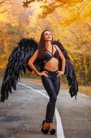 vacker kvinna med svarta vingar i höstskog foto