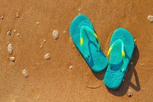 kvinnors flip flops stå på stranden på sanden, semester koncept foto