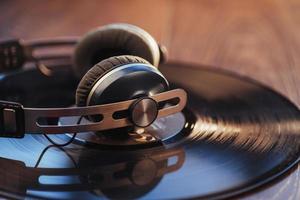 vinylskiva och hörlurar över träbord. ljudentusiast, musikälskare eller professionell discjockeyutrustning. foto