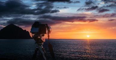 solnedgång över havet, kusten. västra eldklot av solen ovanför horisonten i en färgglad orange himmel. foto