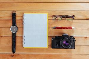 klocka, kamera och anteckningsbok på en brun bakgrund foto
