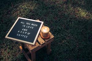 en kopp kaffe och citat på brevtavlan liggande på träbord i trädgården, kärlek och kaffecitat foto