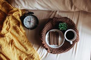 ovanifrån av mellanmål och en kopp kaffe till frukost med suckulent och klockan som visar klockan 7 på sängen foto