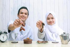 suddigt foto av muslimska par som ler och erbjuder datum till hands i kameran selektivt fokus på händer
