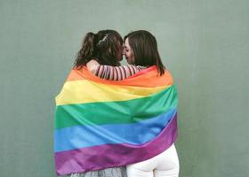 unga kvinnor vänner viftar hbt-flagga med stolthet på gatan foto