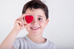 leende barn med ett hjärta som täcker ögat foto
