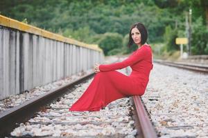 eftertänksam kvinna sitter på tågspåren foto