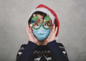 god jul, roligt barn med medicinsk mask och roliga julglasögon foto