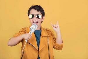 barn med solglasögon som håller en mikrofon gör rocksymbol med händerna upp foto
