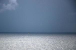 liten vit segelyacht vid horisonten i finlandsviken, Östersjön foto