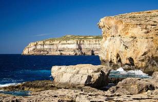 stenig kustlinje klippor nära kollapsade azurblå fönster, gozo island, malta foto