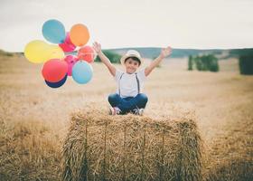 lyckligt barn med ballonger i vetefält foto