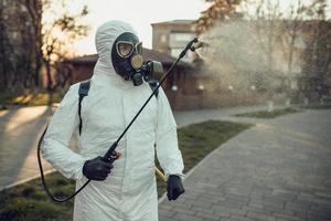 rengöring och desinfektion på lekplatsen i stadskomplexet mitt i coronavirusepidemiteam för desinfektionsinsatser infektionsförebyggande och kontroll av epidemiskyddsdräkt och mask foto