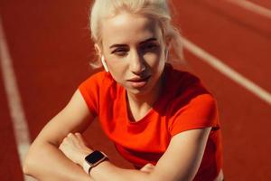 närbild porträtt av en vacker blondin som sitter på en joggingbana foto
