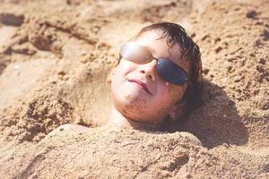 pojke med solglasögon på stranden foto