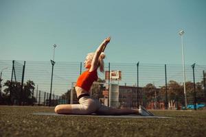 vacker blondin gör stretching på gräsmattan på en fotbollsplan foto