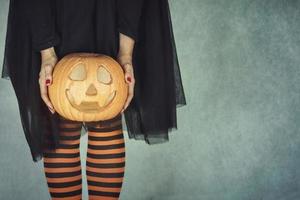 närbild kvinnas ben med halloween pumpa foto