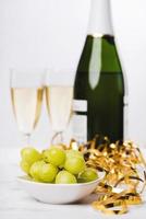 nyårsafton firande koncept bakgrund. närbild av druvor med champagneflaska och och två glas suddig i bakgrunden. selektiv fokus, suddig bakgrund foto