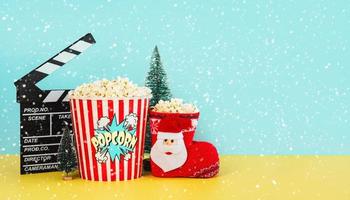 film clapperboard med popcorn, julprydnad, snöflingor och utrymme för text. jul filmer koncept foto