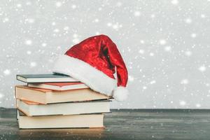 merry christmas.books och jultomten hatt på ett träbord. foto