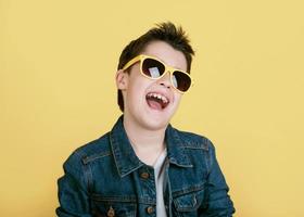 glad och leende pojke med solglasögon över gul bakgrund foto