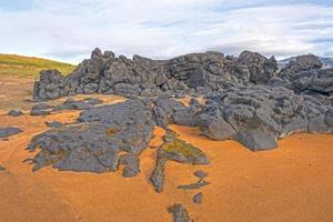 vulkanisk sten mitt på sandstranden foto