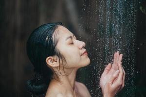 vacker ung asiatisk kvinna koppla av medan du tar en dusch foto