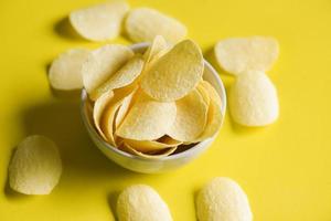 potatischips snack på skål och gul bakgrund, krispiga potatischips på köket foto