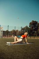 vacker blondin gör stretching på gräsmattan på en fotbollsplan foto
